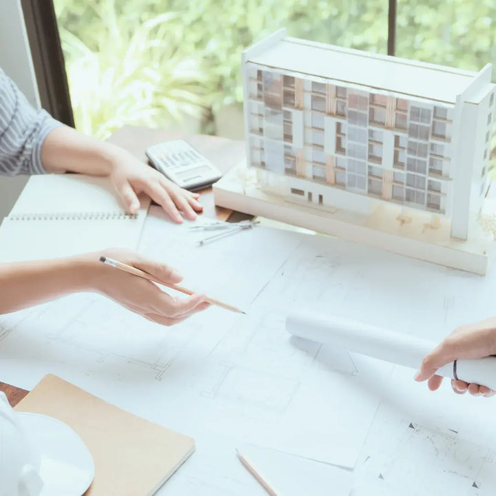 Profesionales revisando planos arquitectónicos y maqueta para desarrollar soluciones de accesibilidad universal en entornos construidos.

