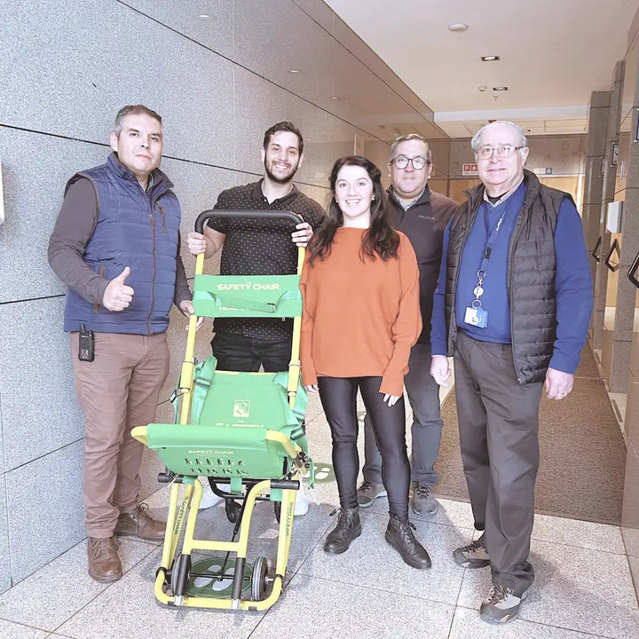 Equipo de BAU Accesibilidad capacitando a personal en el uso de silla de evacuación para emergencias en edificios.